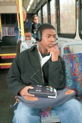 Photo of a teenager listening to a Talking Book on a bus.